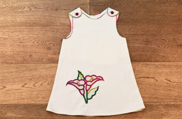 Vestido de niña decorado con flores de Alcatraz bordadas.