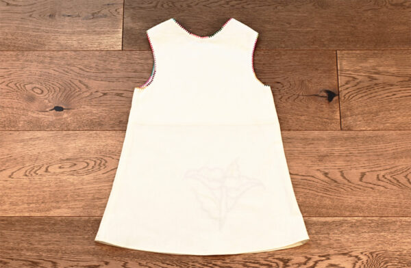 Vestido de niña decorado con flores de Alcatraz bordadas.